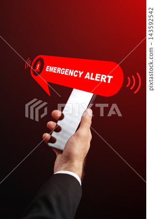Emergency alert notification on a smartphone with a hand holding the device in a dark background 143592542