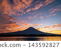 Mount Fuji and the sunrise clouds stretching across the sky as seen from Lake Tanuki. 143592827