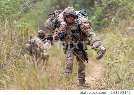 Soldier carrying injured comrade through tall grassy terrain with focused determination Soldier carrying injured comrade through tall grassy terrain with focused determination 143593341