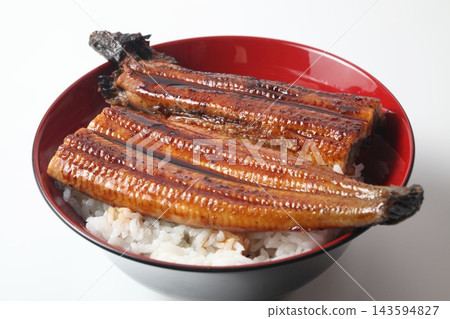 A close-up of a rice bowl topped with glossy grilled eel. 143594827