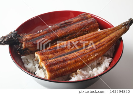 A close-up of a rice bowl topped with glossy grilled eel. A close-up of a rice bowl topped with glossy grilled eel. 143594830