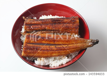A close-up of a rice bowl topped with glossy grilled eel. A close-up of a rice bowl topped with glossy grilled eel. 143594833