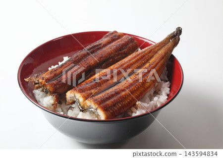 A close-up of a rice bowl topped with glossy grilled eel. A close-up of a rice bowl topped with glossy grilled eel. 143594834