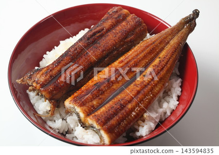 A close-up of a rice bowl topped with glossy grilled eel. A close-up of a rice bowl topped with glossy grilled eel. 143594835