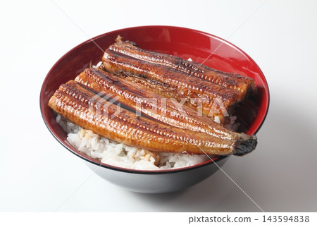 A close-up of a rice bowl topped with glossy grilled eel. A close-up of a rice bowl topped with glossy grilled eel. 143594838