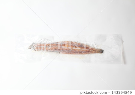 One whole grilled eel in a vacuum-sealed package, against a white background. 143594849