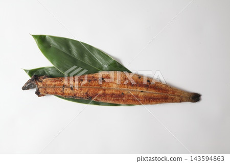 A whole grilled eel placed on a bamboo leaf, against a white background. A whole grilled eel placed on a bamboo leaf, against a white background. 143594863