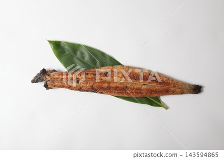 A whole grilled eel placed on a bamboo leaf, against a white background. A whole grilled eel placed on a bamboo leaf, against a white background. 143594865