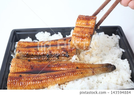 A piece of eel bento (unaju) lifted with chopsticks. A piece of eel bento (unaju) lifted with chopsticks. 143594884