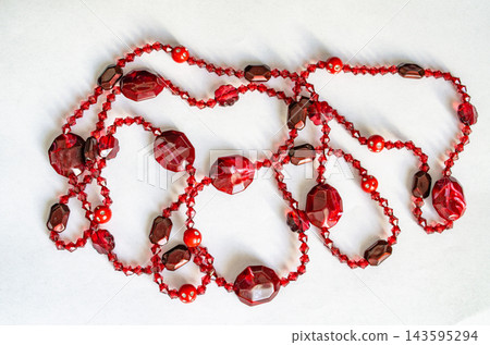 Colorful necklace made with red and brown beads laid out on a white surface 143595294