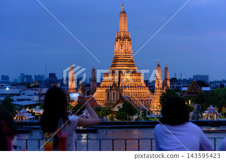 Bangkok, Thailand - June 11, 2025: Evening view of tourists watching the sunset along the Chao Phraya River at Wat Arun. Bangkok, Thailand - June 11, 2025: Evening view of tourists watching the sunset along the Chao Phraya River at Wat Arun. 143595423