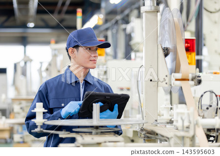 一名外籍男性工人在製造廠工作時操作平板電腦。 一名外籍男性工人在製造廠工作時操作平板電腦。 143595603