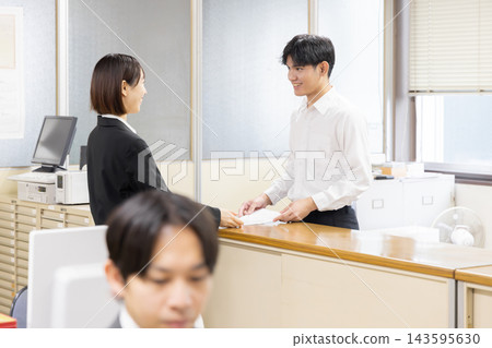 一位外國居民在日本市政廳提交行政申請文件的場景。 一位外國居民在日本市政廳提交行政申請文件的場景。 143595630