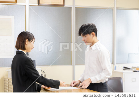一位外國居民在日本市政廳提交行政申請文件的場景。 143595631