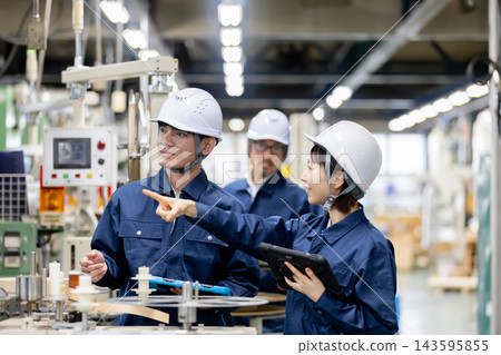 在一家製造工廠裡,一名外國男工人和一名日本女工人正在用平板電腦討論生產設備。 在一家製造工廠裡,一名外國男工人和一名日本女工人正在用平板電腦討論生產設備。 143595855