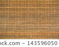 Close-up of a natural bamboo mat or blind, featuring horizontal light brown wooden slats intricately woven together with contrasting white threads. A rustic and textured background. 143596050