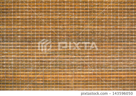 Close-up of a natural bamboo mat or blind, featuring horizontal light brown wooden slats intricately woven together with contrasting white threads. A rustic and textured background. Close-up of a natural bamboo mat or blind, featuring horizontal light brown wooden slats intricately woven together with contrasting white threads. A rustic and textured background. 143596050