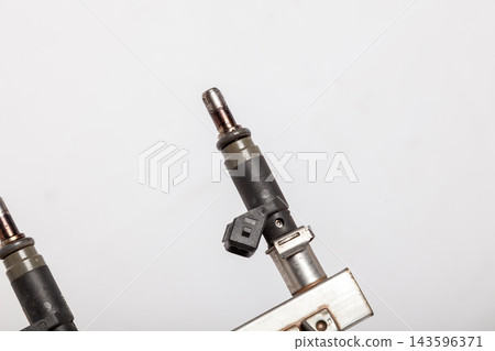 Close-up on a car fuel injector for supplying gasoline to cylinder engine on a white isolated background. Spare parts catalog Close-up on a car fuel injector for supplying gasoline to cylinder engine on a white isolated background. Spare parts catalog 143596371