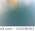 The clear sky is reflected on the pale green surface of the water. 143596561