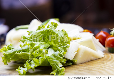 cheese and lettuce on wooden plate 143598216