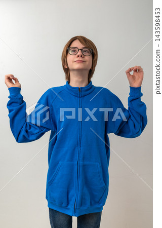 Young person wearing a blue fleece jacket and glasses, standing against a white background, looking up with an expression of hope and outstretched hands, symbolizing wonder and aspiration 143598453