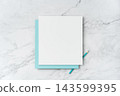 Top view of blank white and blue square greeting card with pencil mockup on marble background with copy space 143599395