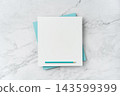 Top view of blank white and blue square greeting card with pencil mockup on marble background with copy space 143599399