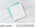 Top view of blank white and blue square greeting card mockup on marble background with copy space 143599400