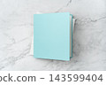 Top view of blank white and blue open square greeting card mockup on marble background with copy space 143599404