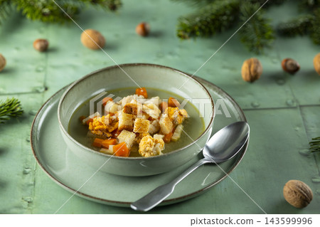 Vegetable soup with croutons and nuts on green background Vegetable soup with croutons and nuts on green background 143599996