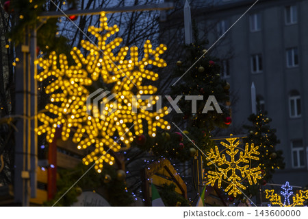 Glowing snowflake lights decorating a festive Christmas market Glowing snowflake lights decorating a festive Christmas market 143600000