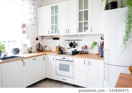 Symmetric wide shot of a modern scandinavian kitchen lower bases with built in oven and stovetop, home design, cozy lifestyle. Symmetric wide shot of a modern scandinavian kitchen lower bases with built in oven and stovetop, home design, cozy lifestyle. 143600475