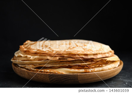 Stack of fresh thin pancakes on black table Stack of fresh thin pancakes on black table 143601039