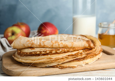 Stack of fresh thin pancakes on wooden board, closeup Stack of fresh thin pancakes on wooden board, closeup 143601044