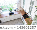 Top view of a bright minimalist kitchen with white furniture and natural wooden work surface, home design, cozy lifestyle. 143601257