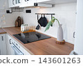 Close up of a black induction stovetop built into a warm wood kitchen counter with kitchen hooks, home design, cozy lifestyle. 143601263