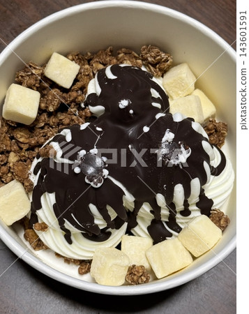 Swirled yogurt ice cream dessert served in a cup, smooth creamy texture with glossy surface, topped with fresh fruit pieces, highlighting its refreshing and inviting appearance in detail 143601591