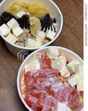 Swirled yogurt ice cream dessert served in a cup, smooth creamy texture with glossy surface, topped with fresh fruit pieces, highlighting its refreshing and inviting appearance in detail 143601617