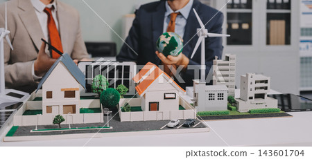 Team presenting a solar and wind energy project with model house, earth globe and green ideas in an office meeting 143601704