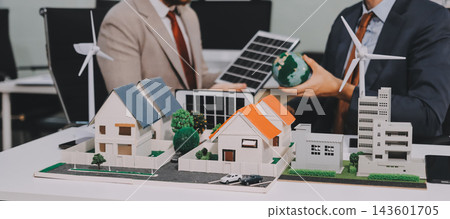 Team presenting a solar and wind energy project with model house, earth globe and green ideas in an office meeting 143601705