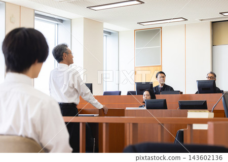 A man testifying before a judge in a courtroom. A man testifying before a judge in a courtroom. 143602136