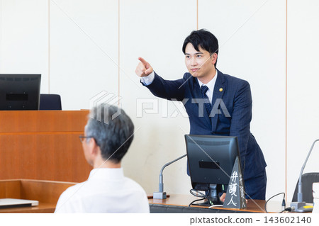 A young male lawyer points his finger and asks a question in a courtroom. A young male lawyer points his finger and asks a question in a courtroom. 143602140