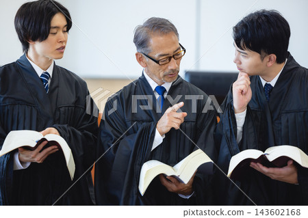 Three judges, a veteran and two younger, discuss while looking at legal texts. Three judges, a veteran and two younger, discuss while looking at legal texts. 143602168