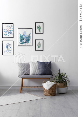 Beautiful paintings of tropical leaves on white wall in living room interior Beautiful paintings of tropical leaves on white wall in living room interior 143602318