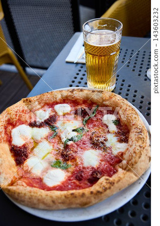 Delicious Neapolitan Pizza and Cold Beer on a Sunny Outdoor Terrace Table Delicious Neapolitan Pizza and Cold Beer on a Sunny Outdoor Terrace Table 143603232