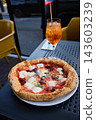 Delicious Neapolitan Pizza and Refreshing Aperol Spritz Cocktail on a Sunny Terrace 143603239