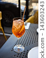 Refreshing Aperol Spritz Cocktail with Orange Slice and Ice on an Outdoor Terrace Table 143603243