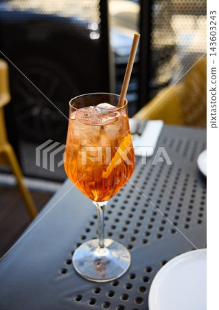 Refreshing Aperol Spritz Cocktail with Orange Slice and Ice on an Outdoor Terrace Table Refreshing Aperol Spritz Cocktail with Orange Slice and Ice on an Outdoor Terrace Table 143603243