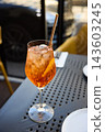 Refreshing Aperol Spritz Cocktail with Orange Slice and Ice on an Outdoor Terrace Table 143603245