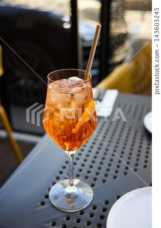 Refreshing Aperol Spritz Cocktail with Orange Slice and Ice on an Outdoor Terrace Table 143603245